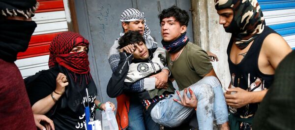 متظاهرون عراقيون يحملون رجلاً متأثراً بالغاز المسيل للدموع أثناء الاحتجاجات المستمرة المناهضة للحكومة في بغداد - سبوتنيك عربي