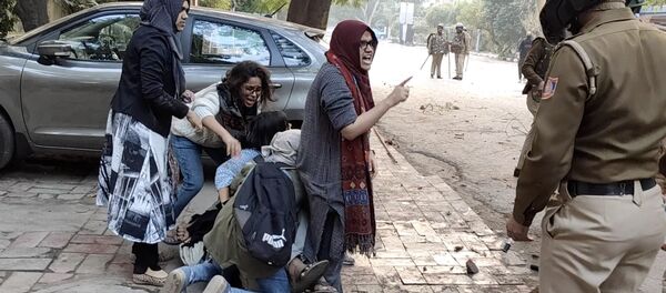 نساء يشكلن درعًا بشريًا حول رجل تعرض للضرب على أيدي الشرطة أثناء الاحتجاجات على قانون الجنسية الجديد في جامعة جامعيا الإسلامية في نيودلهي - سبوتنيك عربي