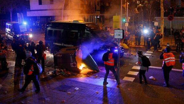  سيارة للشرطة تتخطى سلة محترقة بينما يتجمع المحتجون في برشلونة خلال مباراة كرة القدم بين برشلونة وريال مدريد - سبوتنيك عربي