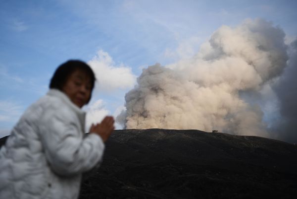 امرأة على خلفية بركان نشط في مدينة آسو في محافظة كوماموتو، اليابان 14 ديسمبر 2019 - سبوتنيك عربي