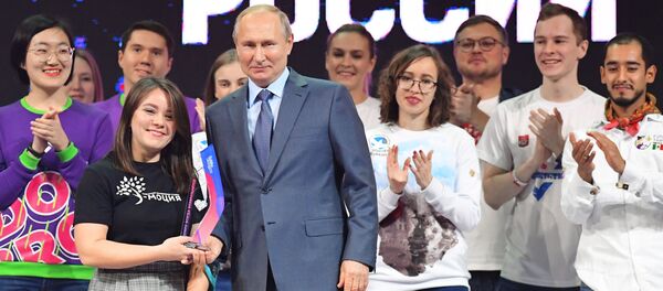 الرئيس الروسي فلاديمير بوتين يقدم الجائزة للفائزة، إنيسا كليوكينا، في مسابقة عموم روسيا التطوع لروسيا 2019 في ترشيح تطوع العام في ختام فعاليات منتدى متطوع روسيا، 5 ديسمبر 2019 - سبوتنيك عربي