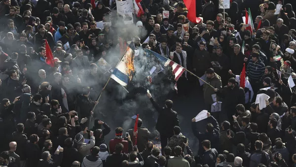 مشيعون في ميدان الثورة الإسلامية في طهران يحرقون أعلام الولايات المتحدة وإسرائيل خلال مراسم تشييع للجنرال الإيراني قاسم سليماني ورفاقه الذين قتلوا في العراق في غارة أمريكية بطائرة دون طيار يوم الجمعة  - سبوتنيك عربي
