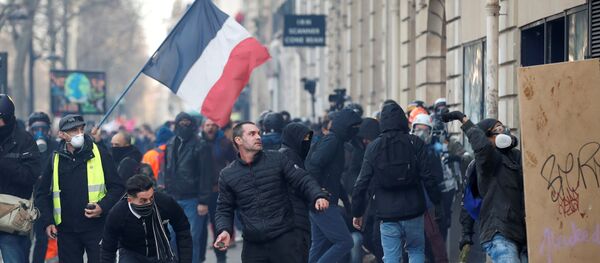 متظاهر يحمل حجرا خلال مظاهرة لأعضاء النقابات العمالية والعمال الفرنسيين، 11 يناير/ كانون الثاني 2020 - سبوتنيك عربي