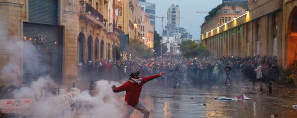 متظاهر يرمي علبة غاز مسيل للدموع أثناء احتجاج ضد نخبة حاكمة متهمة بتوجيه لبنان نحو أزمة اقتصادية في بيروت - سبوتنيك عربي