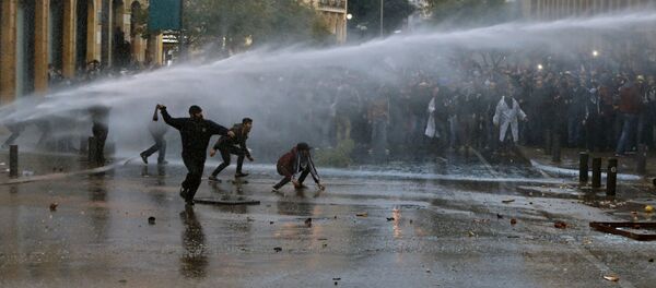 متظاهرون مناهضون للحكومة يشتبكون مع شرطة مكافحة الشغب التي أطلقت عليهم مدافع المياه وقنابل الغاز في طريق يؤدي إلى مبنى البرلمان في بيروت في لبنان السبت 18 يناير  2020 - سبوتنيك عربي