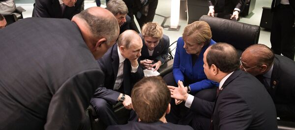 الرئيس الروسي فلاديمير بوتين والمستشارة الألمانية أنغيلا ميركل يتحدثان خلال اجتماع على هامش مؤتمر سلام دولي حول ليبيا في برلين - سبوتنيك عربي