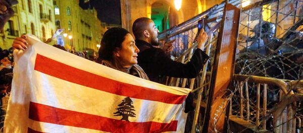 متظاهرة تحمل العلم اللبناني خلال مظاهرة ضد نخبة حاكمة متهمة بتوجيه لبنان نحو الأزمة الاقتصادية في بيروت - سبوتنيك عربي