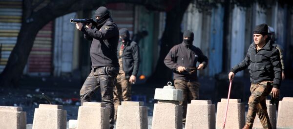 أحد أفراد قوات الأمن العراقية يطلق الغاز المسيل للدموع على المتظاهرين خلال الاحتجاجات المستمرة المناهضة للحكومة في بغداد - سبوتنيك عربي