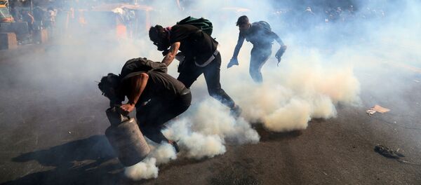 المتظاهرون يرمون الغاز المسيل للدموع مرة أخرى خلال الاحتجاجات المستمرة المناهضة للحكومة في بغداد - سبوتنيك عربي