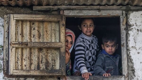 عائلة فلسطسنية في مخيم اللاجئين في خان يونس تطل من نافذة، جنوب قطاع غزة، فلسطين 28 يناير 2020 - سبوتنيك عربي