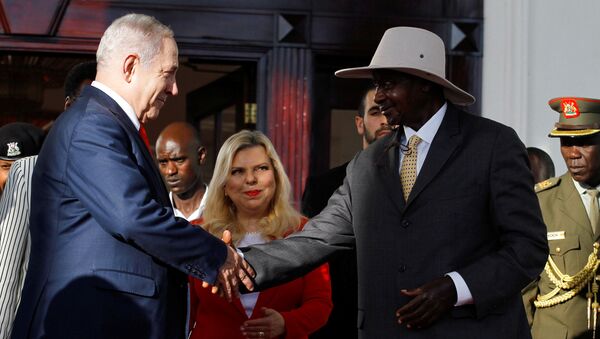 رئيس الوزراء الإسرائيلي بنيامين نتنياهو يصافح الرئيس الأوغندي يوويري موسيفيني في عنتيبي بينما تنظر زوجته سارة نتنياهو - سبوتنيك عربي