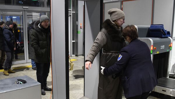 موظفة في مطار كادالا في تشيتا في روسيا ترتدي قناع الوجه تتفقد راكبة بعد تفشي فيروس كورونا - سبوتنيك عربي