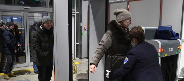 موظفة في مطار كادالا في تشيتا في روسيا ترتدي قناع الوجه تتفقد راكبة بعد تفشي فيروس كورونا - سبوتنيك عربي