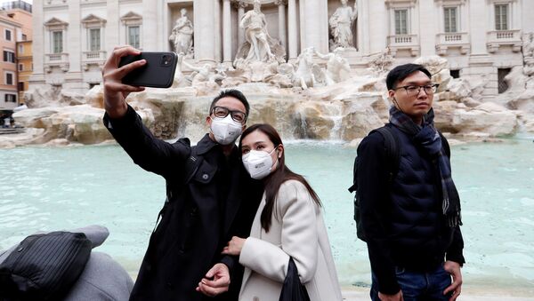 سياح يرتدون أقنعة واقية بعد تأكيد حالات الإصابة بفيروس كورونا في إيطاليا، يلتقطون صورة سيلفي أمام نافورة تريفي في روما، 31 يناير 2020 - سبوتنيك عربي