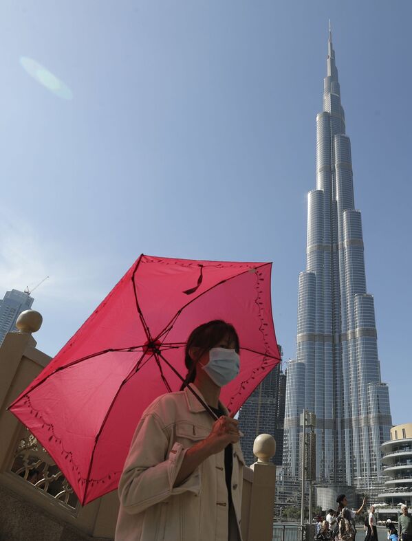 امرأة ترتدي قناعا واقيا في دبي، تلتقط صورة على خلفية برج خليفة، بعد تأكيد حالات الإصابة بفيروس كورونا في الإمارات العربية المتحدة 30 يناير 2020 - سبوتنيك عربي