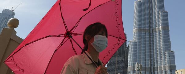 امرأة ترتدي قناعا واقيا في دبي، تلتقط صورة على خلفية برج خليفة، بعد تأكيد حالات الإصابة بفيروس كورونا في الإمارات العربية المتحدة 30 يناير 2020 - سبوتنيك عربي