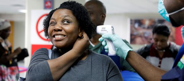 مسافرة تصل إلى هايتي في مطار توسان لوفرتور الدولي تتحقق من درجة حرارتها بواسطة عامل من وزارة الصحة العامة والسكان الهايتية في بورت أو برنس - سبوتنيك عربي