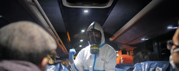 ضابط يرتدي زيا واقيا يعطي ارشادات بشأن عملية اجلاء المواطنين من مدينة ووهان، 2 فبراير 2020 - سبوتنيك عربي