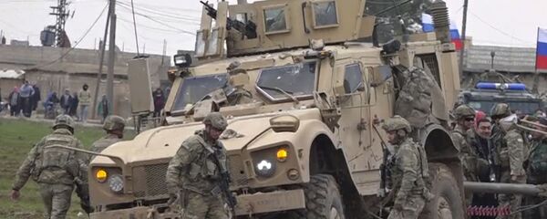 جنود تجمعوا بجانب قافلة عسكرية أمريكية عالقة في قرية خربة عمو شرق مدينة القامشلي في سوريا  - سبوتنيك عربي