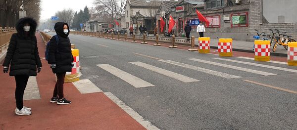 رجلان يرتديان أقنعة الوجه بينما يمشيان في شارع فارغ في بكين في الصين - سبوتنيك عربي