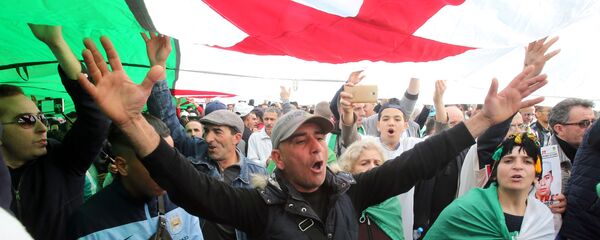 متظاهرون جزائريون يحملون العلم الوطني بعد مرور عام على بدء الاحتجاجات الأسبوعية التي تدعو إلى إصلاح شامل للنخبة الحاكمة ووضع حد للفساد وانسحاب الجيش من السياسة في الجزائر العاصمة  14 فبراير/ شباط 2020 - سبوتنيك عربي