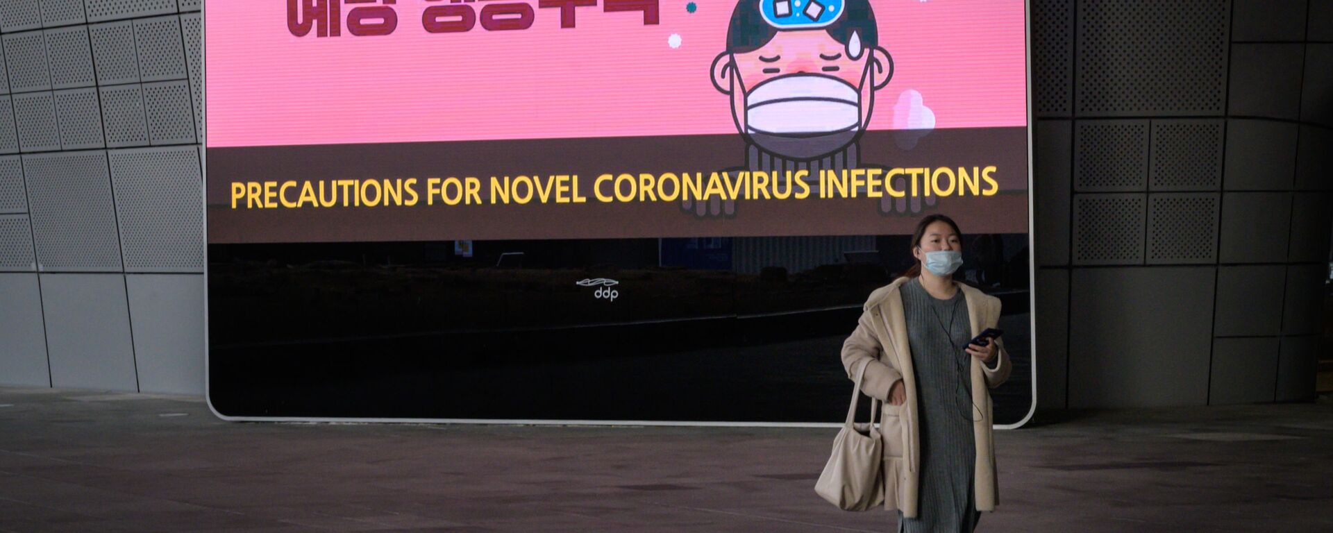 امرأة ترتدي قناعًا أمام شاشة تعرض تدابير وقائية ضد فيروس كورونا الجديد - كوريا الجنوبية - سبوتنيك عربي, 1920, 15.01.2022