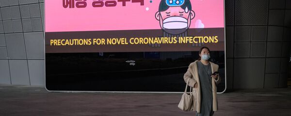 امرأة ترتدي قناعًا أمام شاشة تعرض تدابير وقائية ضد فيروس كورونا الجديد - كوريا الجنوبية - سبوتنيك عربي
