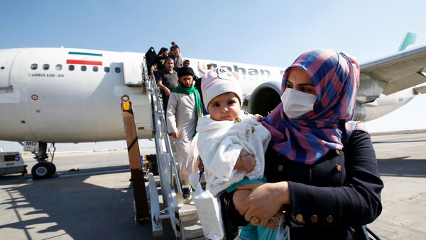 إيرانيون يرتدون أقنعة واقية ينزلون من طائرة فور وصولهم إلى مطار النجف في العراق وسط تفشي فيروس كورونا الجديد - سبوتنيك عربي