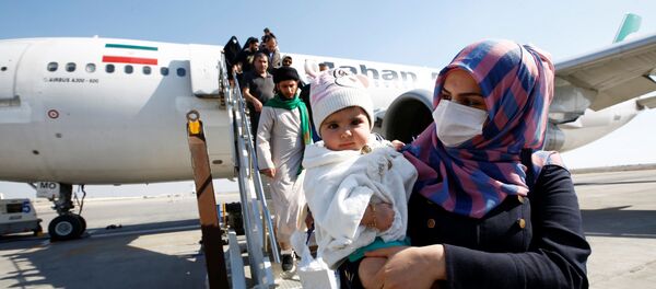 إيرانيون يرتدون أقنعة واقية ينزلون من طائرة فور وصولهم إلى مطار النجف في العراق وسط تفشي فيروس كورونا الجديد - سبوتنيك عربي