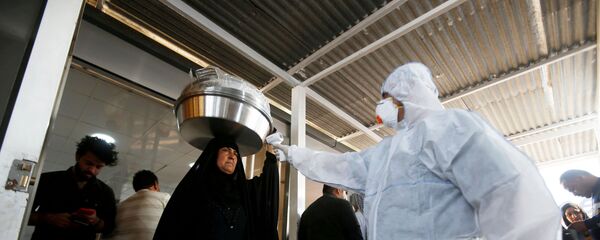 موظف طبي عراقي يفحص درجة حرارة راكبة وسط تفشي فيروس كورونا الجديد لدى وصولها إلى معبر شلامشة الحدودي بين العراق وإيران - سبوتنيك عربي