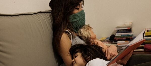 أم وابنتها يجلسون على أريكة في منزل داخل أحد المناطق المصابة بفيروس كورونا - سبوتنيك عربي