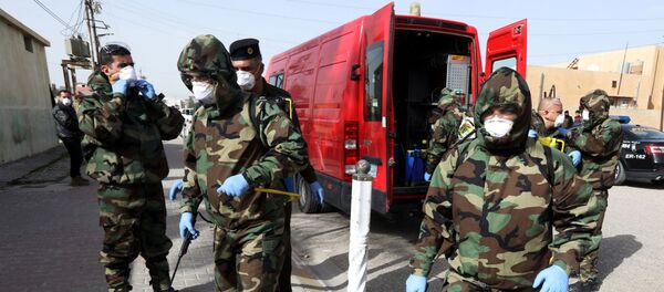 أعضاء فريق الدفاع المدني يستعدون لرش مادة مطهرة لتطهير المنطقة القريبة من منزل الأشخاص المصابين بفيروس كورونا المكتشف في كركوك في العراق - سبوتنيك عربي