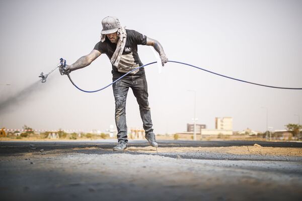 الفنان الفرنسي السويسري سايبي (Saype) خلال عرضه لأعماله الفنية فن الأرض في بوركينا فاسو، 1 مارس 2020 - سبوتنيك عربي