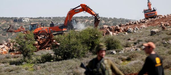 جرافة تحرسها القوات الإسرائيلية تقوم بتجريف الأراضي بالقرب من قرية قصرة الفلسطينية في الضفة الغربية المحتلة - سبوتنيك عربي