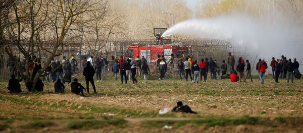 الأمن اليوناني يستخدم خراطيم المياه بينما ينظر المهاجرون بالقرب من معبر بازاركولي الحدودي التركي مع كاستانتس اليونانية بالقرب من أدرنة - سبوتنيك عربي