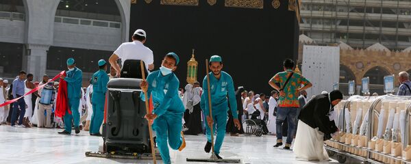 عمال النظافة يرتدون أقنعة واقية للوجه بعد تفشي فيروس كورونا ويمسحون الأرض عند الكعبة المشرفة في المسجد الحرام في مدينة مكة المكرمة - سبوتنيك عربي