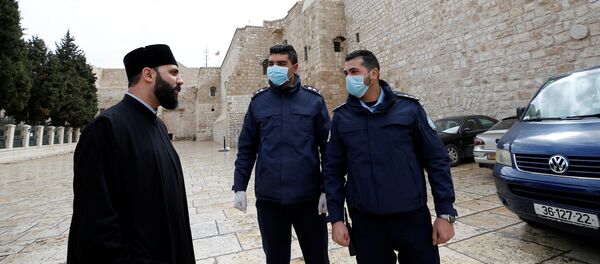 ضباط شرطة فلسطينيون يقفون خارج كنيسة المهد التي تم إغلاقها كإجراء وقائي ضد فيروس كورونا المستجد في بيت لحم بالضفة الغربية المحتلة - سبوتنيك عربي