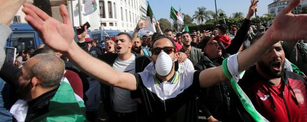 متظاهر يرتدي قناع الوجه خلال احتجاج مناهض للحكومة في الجزائر العاصمة - سبوتنيك عربي