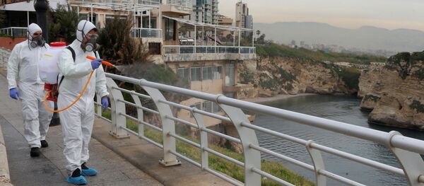 موظفون من شركة مطهرة يعقمون الدرابزين كإجراء احترازي ضد انتشار فيروس كورونا في كورنيش بيروت على شاطئ البحر - سبوتنيك عربي