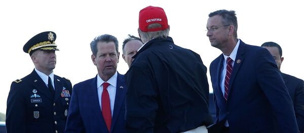 الرئيس الأمريكي دونالد ترامب ينزل من طائرة سلاح الجو الأول في قاعدة دوبينز للحرس الوطني في ماريتا ويصافح النائب المصاب بكورونا - سبوتنيك عربي