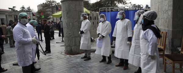 العاملون الصحيون الأفغان ينتظرون لقياس درجة حرارة الضيوف للتحقق من وجود فيروسات تاجية عند بوابة دخول القصر الرئاسي خلال حفل تنصيب الرئيس الأفغاني أشرف غني في كابول  - سبوتنيك عربي