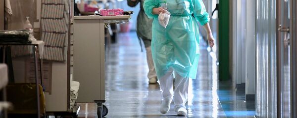 عمال طبيون يرتدون الأقنعة الواقية والبدلات يسيرون في وحدة العناية المركزة في مستشفى Oglio Po حيث يتم علاج المرضى الذين يعانون من مرض فيروس كورونا في إيطاليا - سبوتنيك عربي