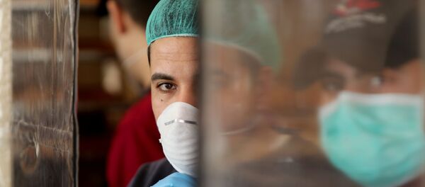 فلسطينيون يرتدون أقنعة كإجراء وقائي ضد مرض فيروس كورونا يعملون في مخبز في مدينة غزة - سبوتنيك عربي