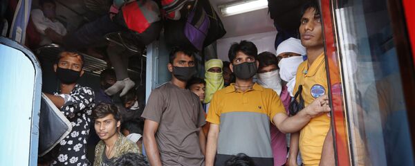 عاملون بأجر يومي يعودون من مومباي إلى قراهم وسط مخاوف من فيروس كورونا في حافلة قطار مزدحمة في براياغراج في الهند - سبوتنيك عربي