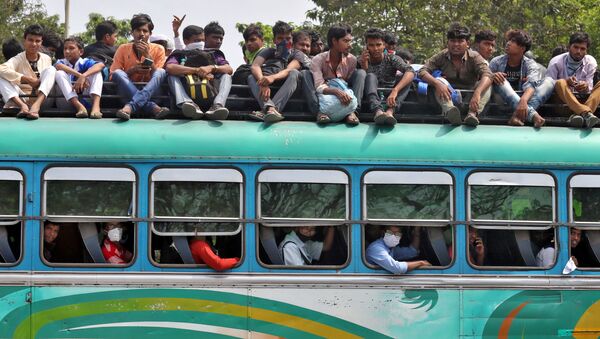 يعود الناس في حافلة مزدحمة إلى مدنهم وقراهم قبل بدء تنفيذ حظر التجول من قبل حكومة ولاية البنغال الغربية للحد من انتشار كوفيد-١٩ (كورونا)، في كلكتا، الهند 23 مارس 2020 - سبوتنيك عربي