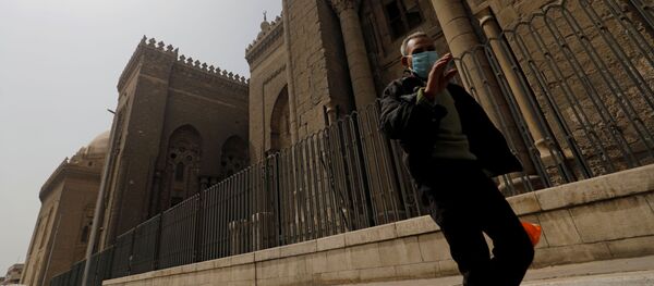 رجل يرتدي قناع وجه يمر بجوار مسجد الرفاعي حيث لم يحضر المسلمون صلاة الجمعة بسبب انتشار مرض كورونا - سبوتنيك عربي