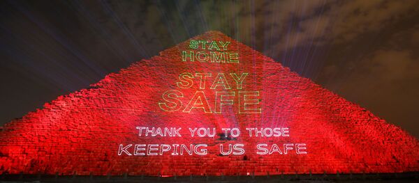 هرم خوفو أهرامات الجيزة مضاء بالنص الذي يشجع على البقاء في المنزل حيث تكثف مصر جهودها لإبطاء انتشار فيروس كورونا - سبوتنيك عربي