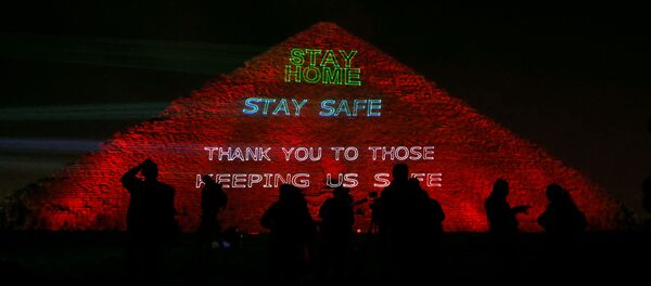 هرم خوفو أهرامات الجيزة مضاء بالنص الذي يشجع على البقاء في المنزل حيث تكثف مصر جهودها لإبطاء انتشار فيروس كورونا - سبوتنيك عربي