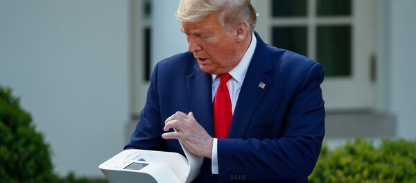 الرئيس الأمريكي دونالد ترامب يفتح علبة اختبار الفيروسات التاجية خلال الإحاطة اليومية بشأن فيروس كورونا في حديقة الورود في البيت الأبيض في واشنطن - سبوتنيك عربي