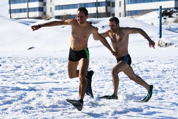 عضوان من نوادي السباحة الشتوية والتصلّب يركضان في إطار فعاليات الاحتفال بعيد ماسلينيتسا (أسبوع المرافع) بالقرب من مستنقع المائي للحي السكني في جنوب غرب نوفوسيبيرسك الروسية، 1 مارس 2020 - سبوتنيك عربي